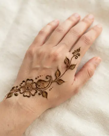 simple Arabic back hand mehndi design with a floral corner motif simple Arabic back hand mehndi design with a floral corner motif